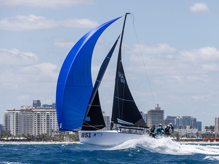 A Melges 24 flying a blue spinnaker racing downwind